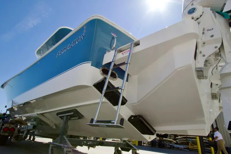 Slide: The Image of 2027 Regulator 35 boat with blue and white hull, ladder, and sunny sky background. - 4