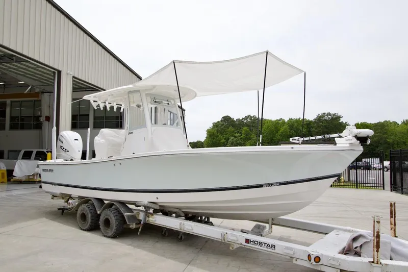 The Image of 2026 Regulator 26XO boat on trailer with canopy, parked outside a building. - 0