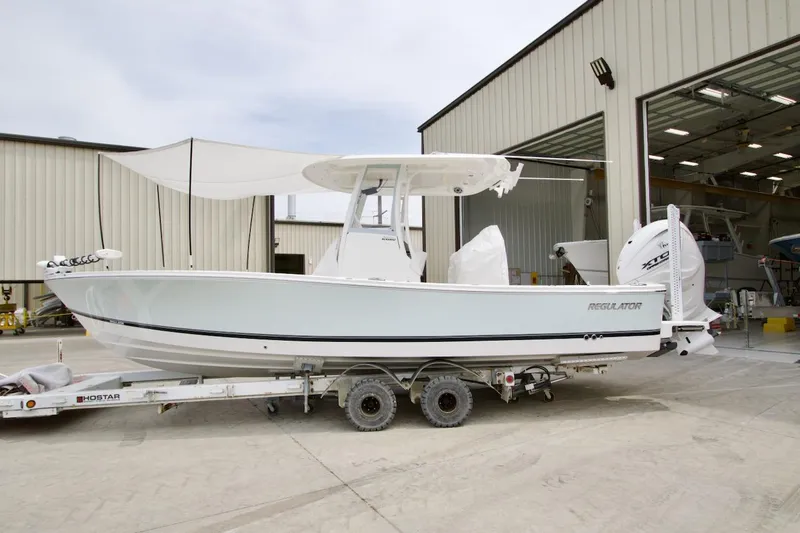 Slide: The Image of 2026 Regulator 26XO boat on trailer outside a large garage. - 1
