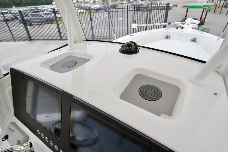 Slide: The Image of 2026 Regulator 26XO boat dashboard with dual screens and compass, parked near a fence. - 11