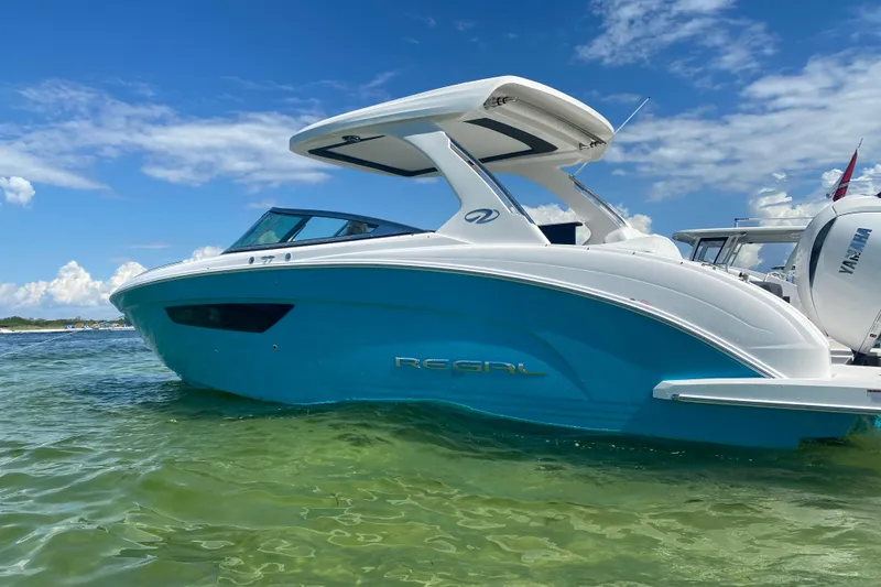 Slide: The Image of 2022 Regal 33 OBX boat on clear water under a blue sky. - 4