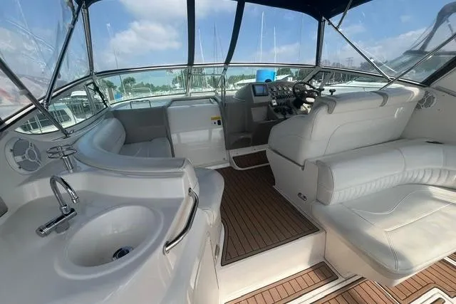 Slide: The Image of 2004 Cruisers Yachts 3372 Express interior with helm, seating, and sink, featuring wood flooring. - 20