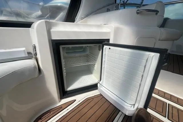 Slide: The Image of Open mini fridge on 2004 Cruisers Yachts 3372 Express, showcasing interior and deck flooring. - 23