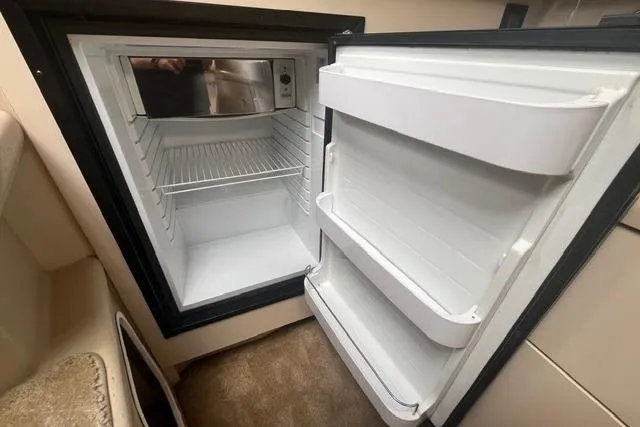 Slide: The Image of Open refrigerator inside 2004 Cruisers Yachts 3372 Express, showcasing interior storage space. - 54