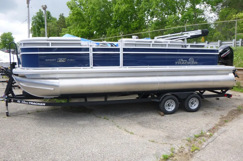 The Image of 2026 Sun Tracker SportFish 22 DLX pontoon boat on trailer, parked outdoors. - 1