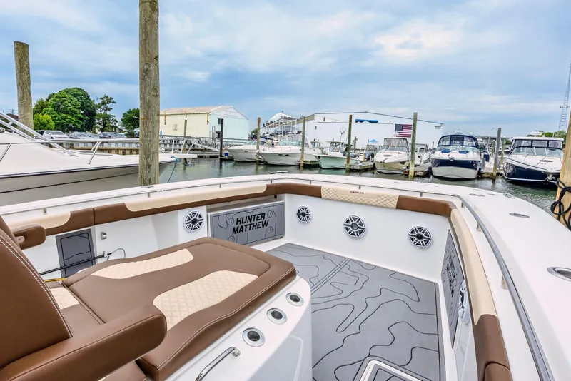 Slide: The Image of 2024 Caymas 34 CT boat interior at marina, featuring brown and beige seating. - 13
