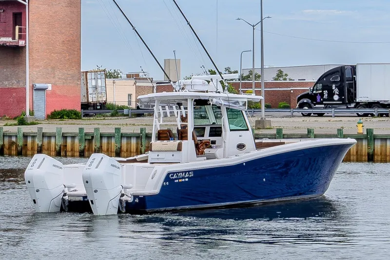 Slide: The Image of 2024 Caymas 34 CT boat with dual Mercury engines on a calm waterfront. - 2