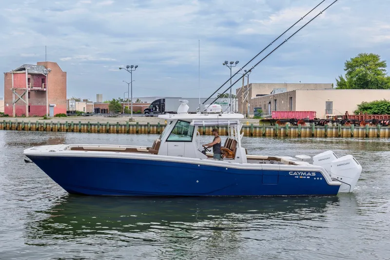 Slide: The Image of 2024 Caymas 34 CT boat cruising on a calm waterway near industrial buildings. - 3