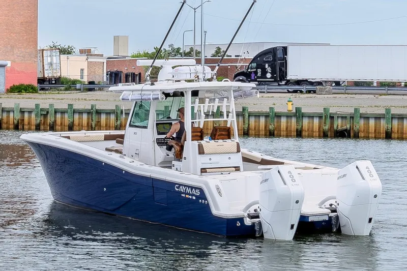 Slide: The Image of 2024 Caymas 34 CT boat with dual Mercury engines on a calm waterfront. - 6