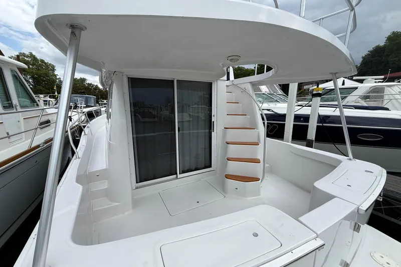 Slide: The Image of 1999 Mainship 350 Trawler with spiral staircase and sliding glass doors, docked at marina. - 4