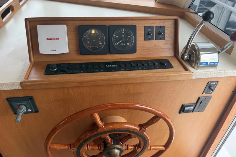 Slide: The Image of 1999 Mainship 350 Trawler helm with wooden wheel, gauges, and throttle controls. - 23