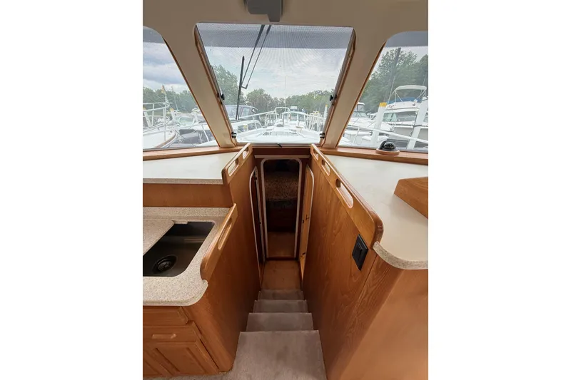 Slide: The Image of Interior view of 1999 Mainship 350 Trawler, featuring wooden cabinetry and steps. - 24