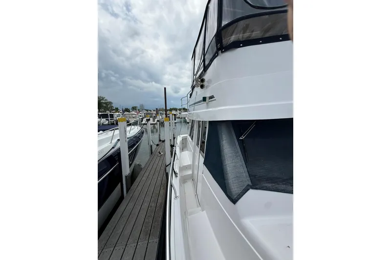 Slide: The Image of 1999 Mainship 350 Trawler docked at marina, cloudy sky in background. - 10