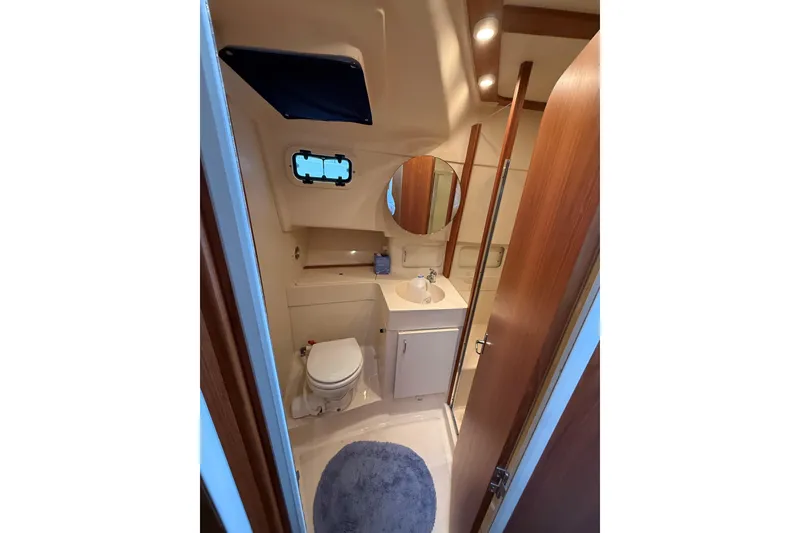 Slide: The Image of Bathroom interior of 1999 Mainship 350 Trawler with sink, toilet, and mirror. - 27