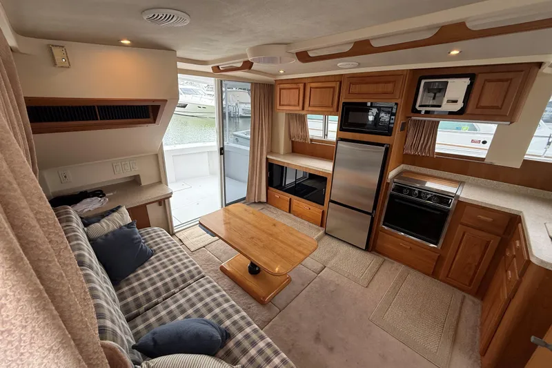 Slide: The Image of Interior of 1999 Mainship 350 Trawler with cozy seating, kitchen, and outdoor view. - 21