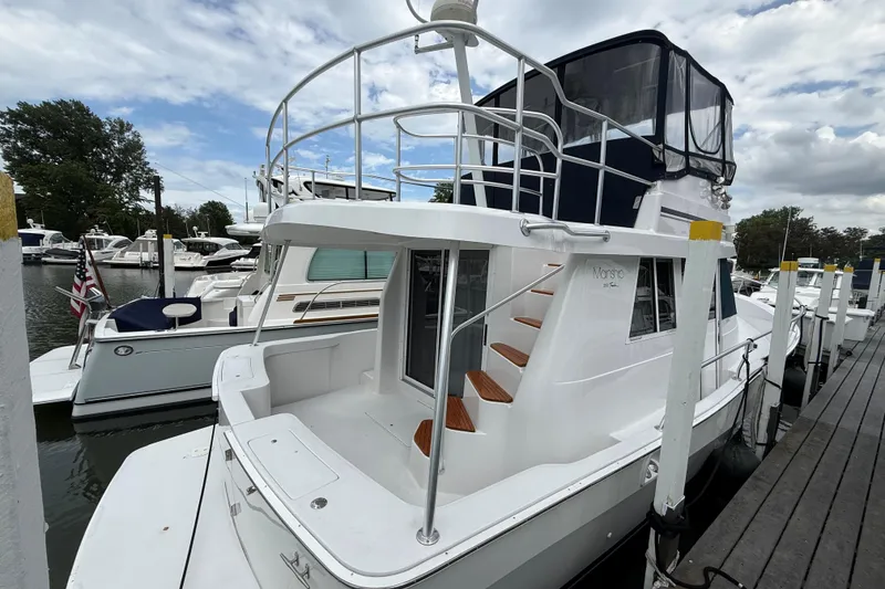 The Image of 1999 Mainship 350 Trawler docked at marina, featuring upper deck and sleek design. - 0