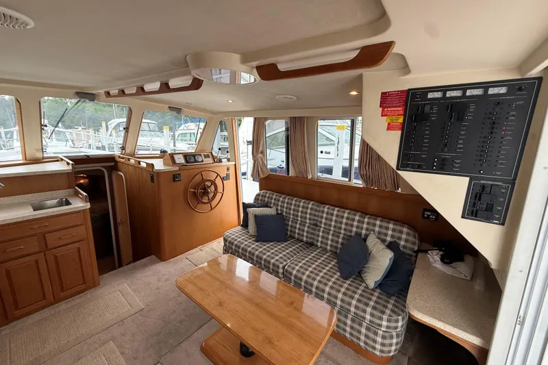 Slide: The Image of Interior of 1999 Mainship 350 Trawler with helm, plaid sofa, and control panel. - 18