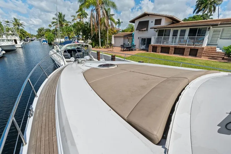 Slide: The Image of 2013 Pershing 64 yacht docked near a waterfront home, surrounded by palm trees. - 11