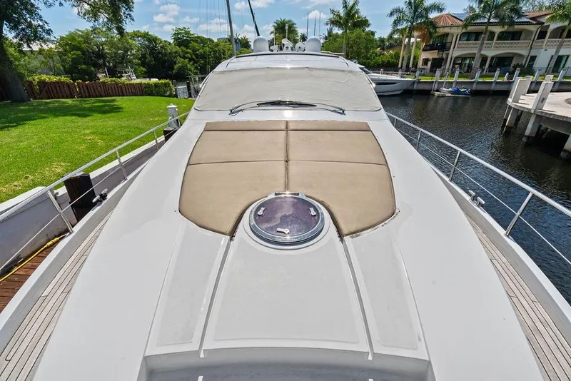Slide: The Image of 2013 Pershing 64 yacht deck with sunpad, docked near waterfront homes. - 12