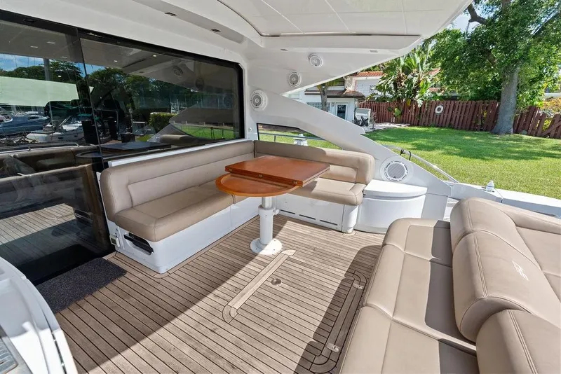 Slide: The Image of Luxurious 2013 Pershing 64 yacht deck with beige seating and wooden table. - 14