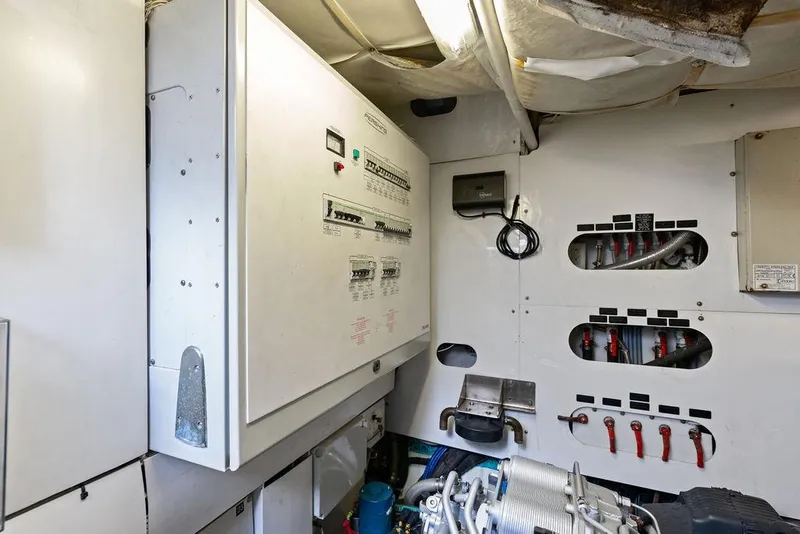 Slide: The Image of Engine room of a 2013 Pershing 64 yacht, featuring control panels and wiring. - 54