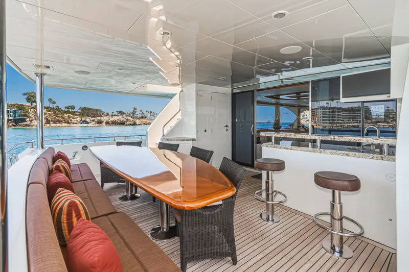 Slide: The Image of Luxurious outdoor area with dining table and bar on a yacht, surrounded by water and coastal scenery. - 24