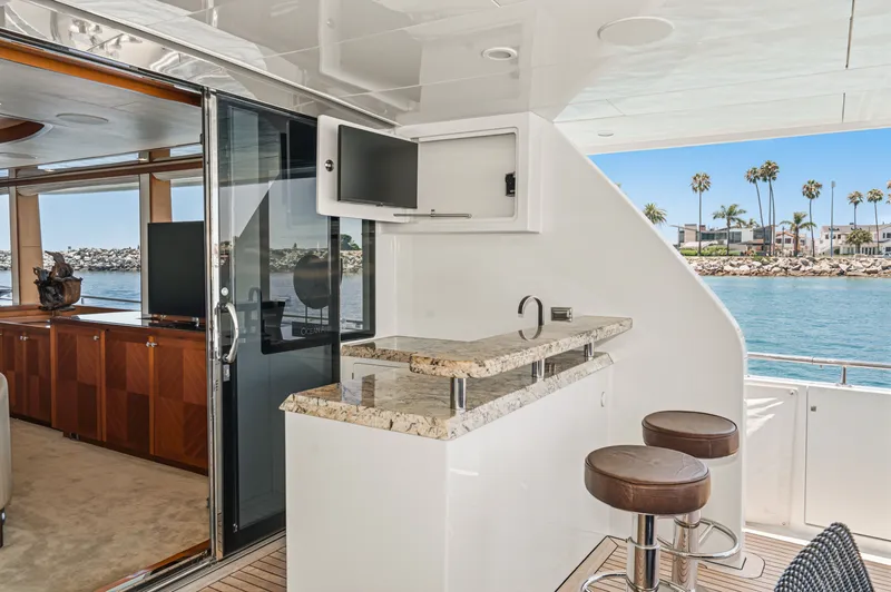 Slide: The Image of Luxurious outdoor area with bar and stools on a yacht, overlooking the sea and palm trees. - 28