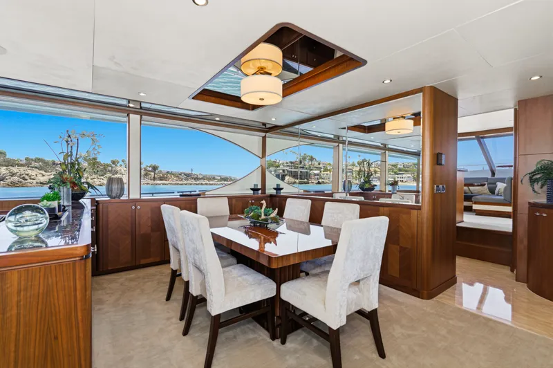 Slide: The Image of Dining area with wooden table and upholstered chairs, surrounded by large windows overlooking the water. - 39