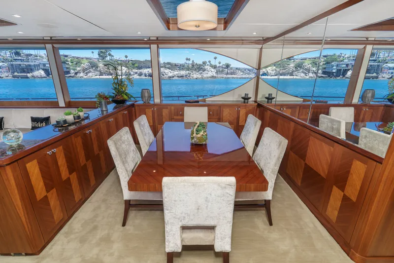 Slide: The Image of Interior view of a luxurious dining area with a wooden table and upholstered chairs, surrounded by large windows with ocean views. - 40