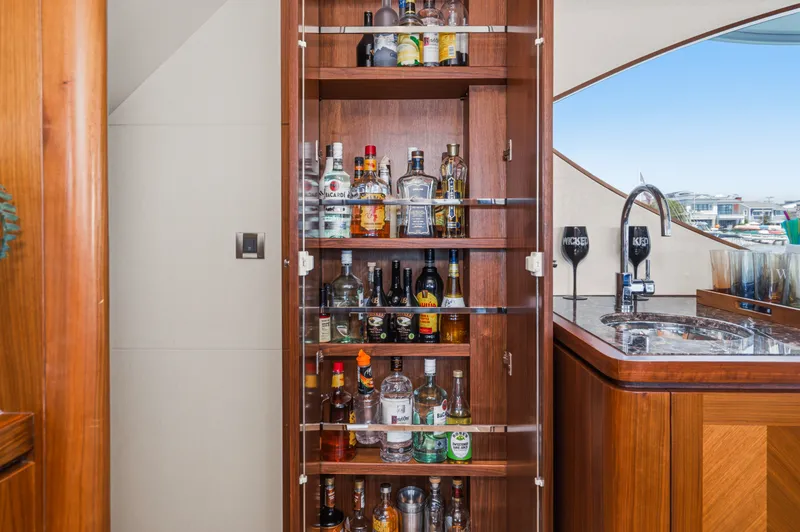Slide: The Image of A well-stocked bar with various liquor bottles in a wooden cabinet on a yacht. - 43