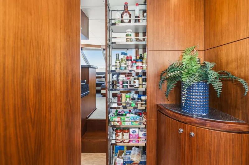 Slide: The Image of Yacht pantry with wood paneling, filled with spices and food items, and a plant. - 45