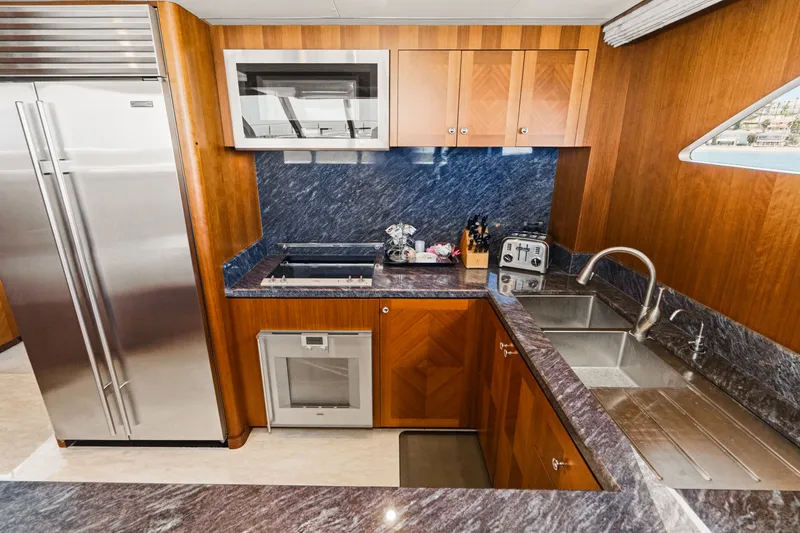 Slide: The Image of The 2015 Ocean Alexander 90 Skylounge Motoryacht's kitchen features modern appliances, wood cabinets, and granite surfaces. - 49