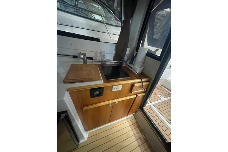 Slide: The Image of 2017 Cutwater C-24 Coupe interior kitchen area with sink and wooden cabinetry. - 13