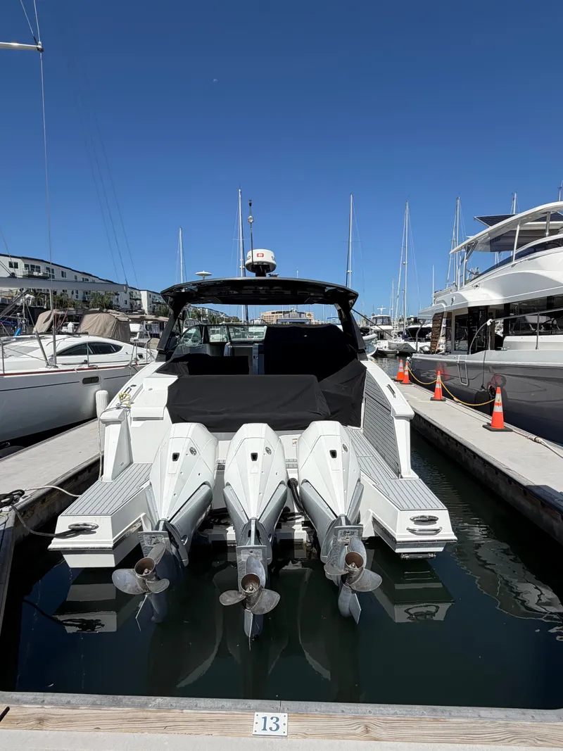 Slide: The Image of A 2021 Cruisers Yachts 38 GLS docked in a marina, featuring three outboard engines. - 4