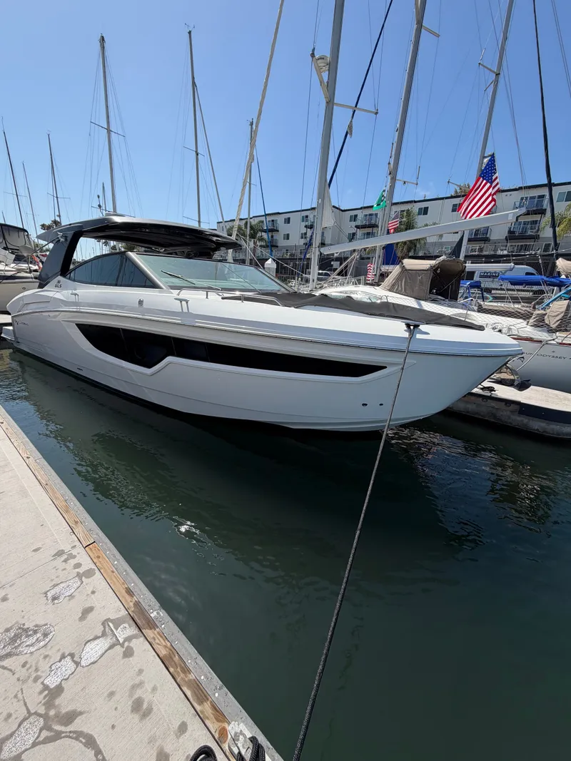Slide: The Image of A modern motor yacht docked, featuring a sleek white design, surrounded by sailboats. - 2