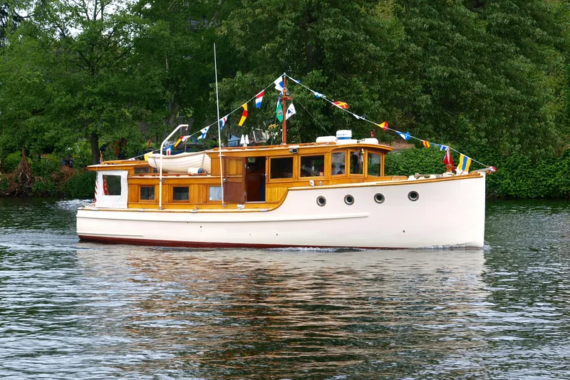 Slide: The Image of Vintage 1942 Grenfell 42 Custom boat adorned with colorful flags on a serene lake. - 14
