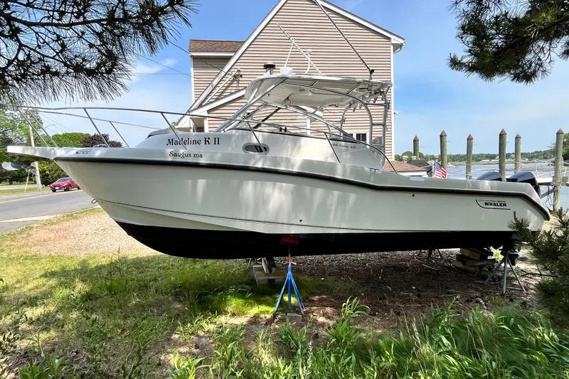 The Image of 2006 Boston Whaler 285 Conquest boat on land, near a waterfront setting. - 0