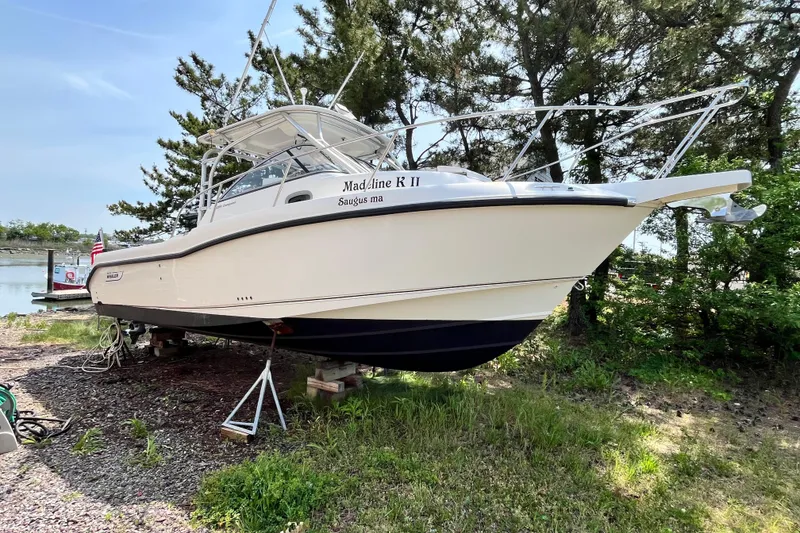 Slide: The Image of 2006 Boston Whaler 285 Conquest boat on land, surrounded by trees and grass. - 1