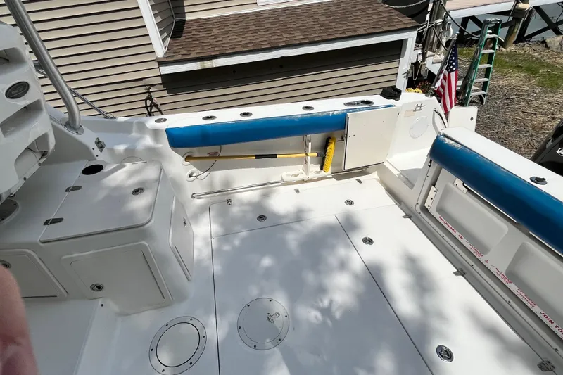 Slide: The Image of 2006 Boston Whaler 285 Conquest boat deck with storage compartments and blue cushioned seating. - 18