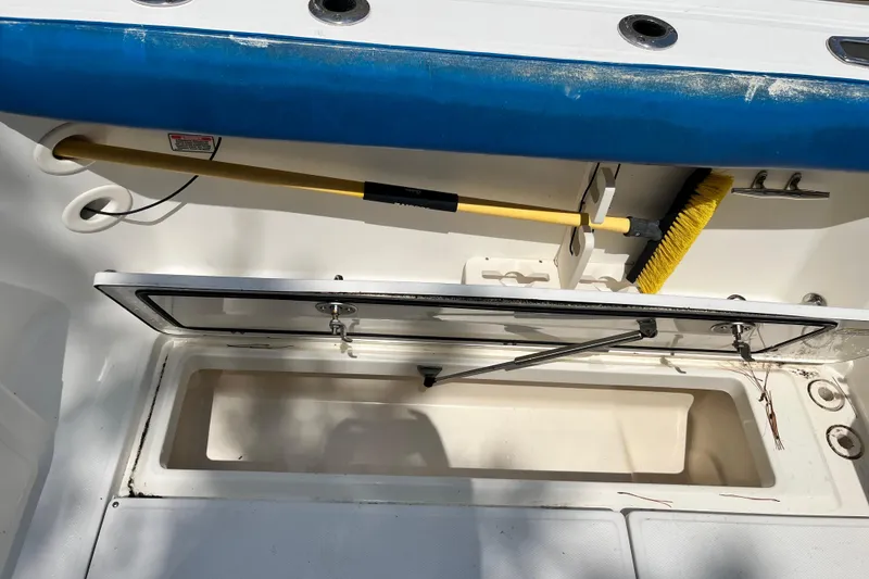 Slide: The Image of Storage compartment on a 2006 Boston Whaler 285 Conquest boat, featuring a cleaning brush. - 22