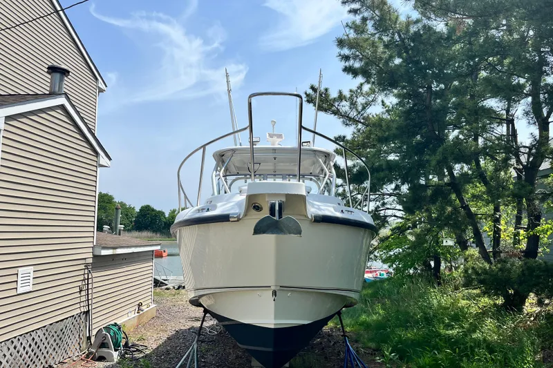 Slide: The Image of 2006 Boston Whaler 285 Conquest boat docked near a house and trees. - 3
