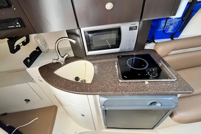 Slide: The Image of Compact kitchen area in a 2006 Boston Whaler 285 Conquest boat, featuring sink, microwave, and stove. - 36