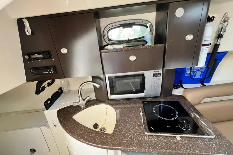 Slide: The Image of 2006 Boston Whaler 285 Conquest cabin kitchen with sink, microwave, and stovetop. - 37