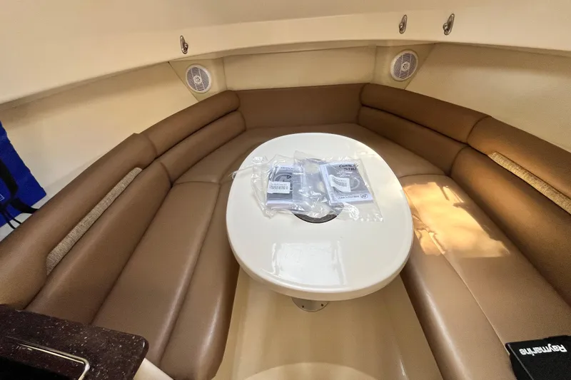 Slide: The Image of 2006 Boston Whaler 285 Conquest cabin interior with brown seating and oval table. - 38