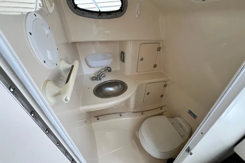 Slide: The Image of 2006 Boston Whaler 285 Conquest boat bathroom with sink, toilet, and storage cabinets. - 39