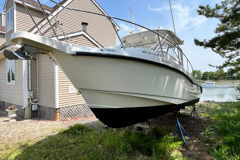 Slide: The Image of 2006 Boston Whaler 285 Conquest boat on land near a house and waterfront. - 4