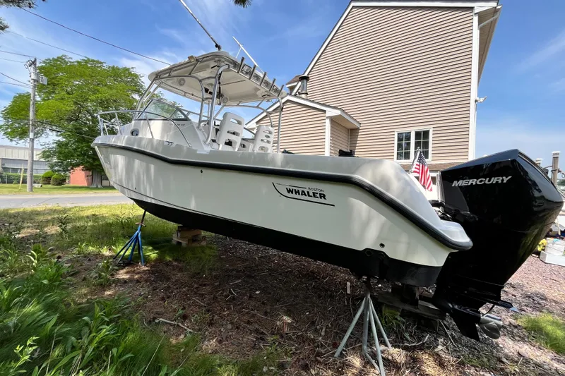 Slide: The Image of 2006 Boston Whaler 285 Conquest boat on stands, with Mercury engine, near a house. - 6