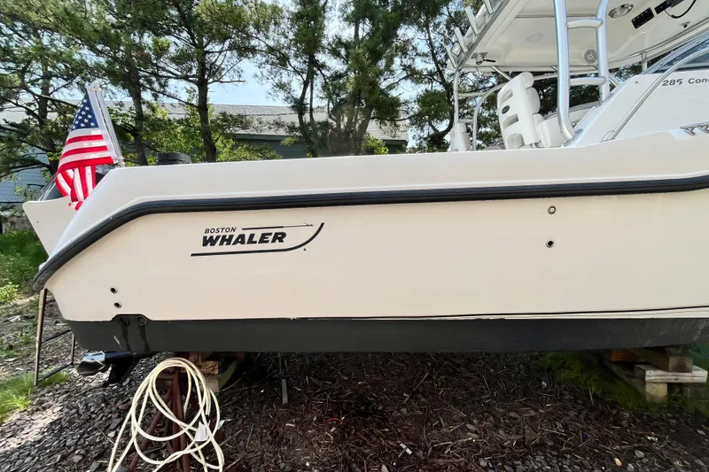 Slide: The Image of 2006 Boston Whaler 285 Conquest boat with American flag, docked on land. - 9