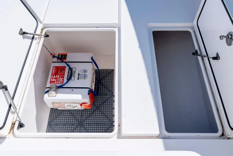 Slide: The Image of Open storage compartments on a 2015 Contender 39 ST boat, featuring a secured life raft. - 22