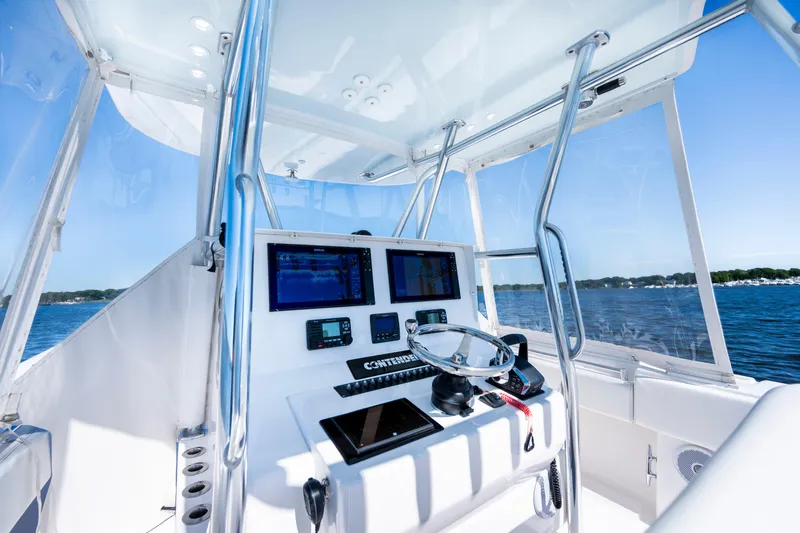 Slide: The Image of 2015 Contender 39 ST boat cockpit with navigation screens and steering wheel on open water. - 23
